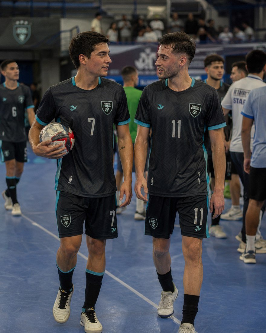 Two futsal teammates in matching dark kits walking off the court