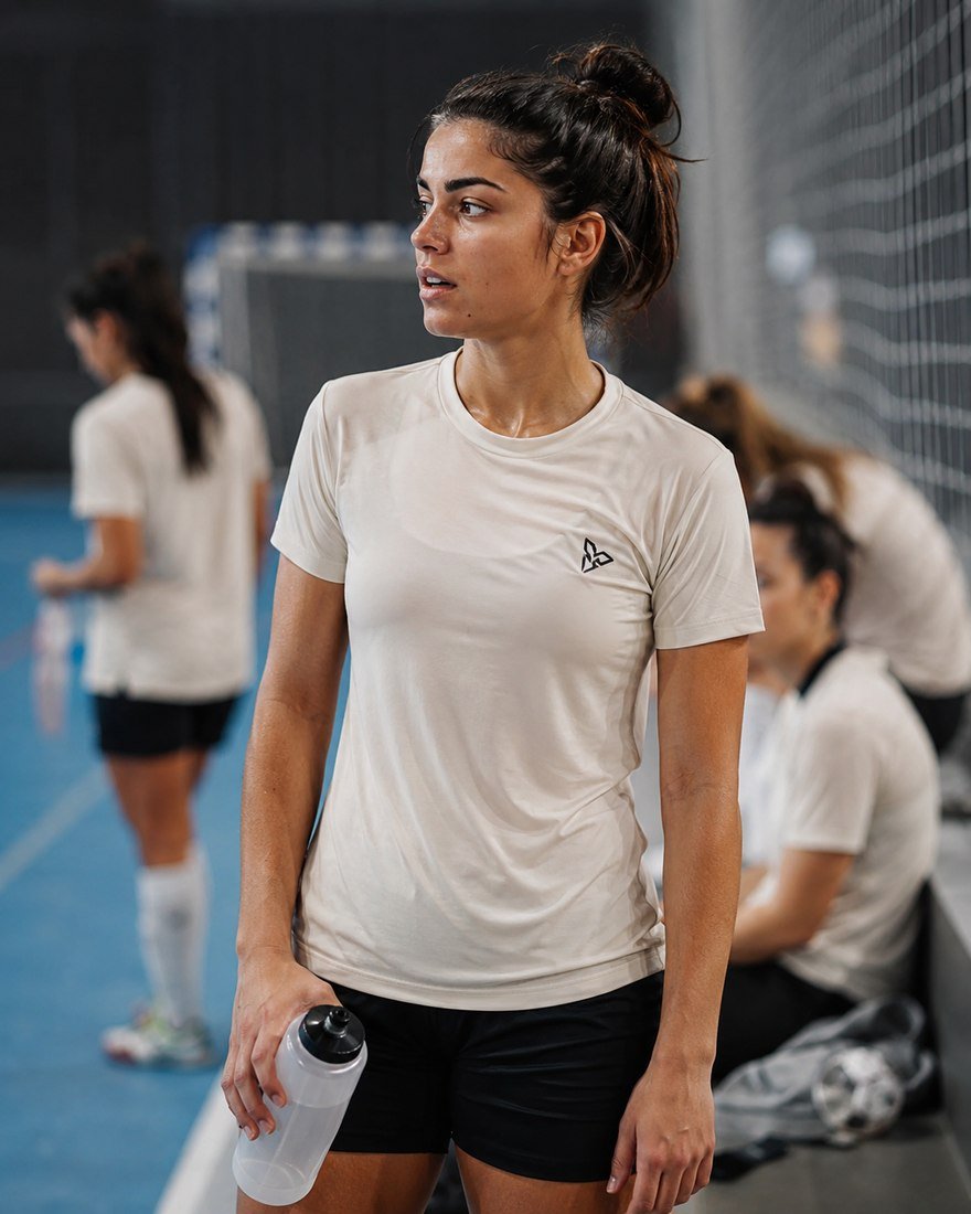 Futsal player in a cream training tee holding a water bottle