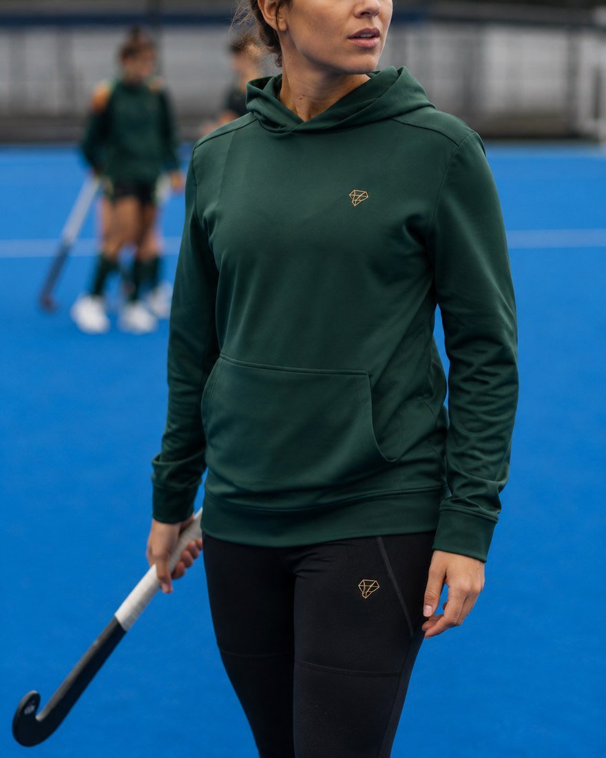 Field hockey player in a green hoodie and leggings